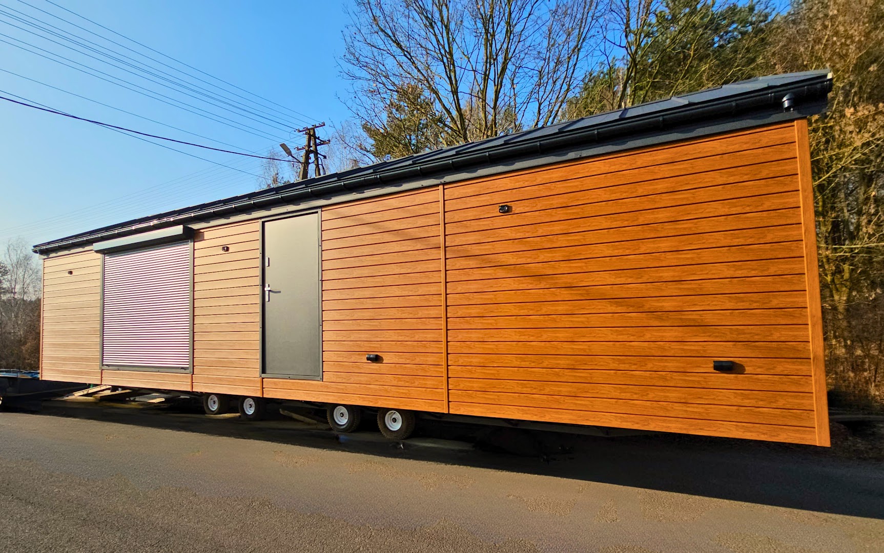 Nowoczesny domek mobilny w wersji transportowej – wydłużony moduł z minimalistycznym wykończeniem i roletami zewnętrznymi zapewniającymi komfort i bezpieczeństwo.